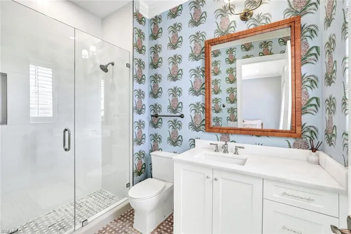 Bathroom with ornamental molding, vanity, toilet, and a shower with door