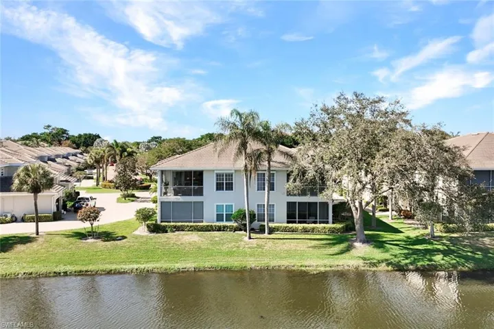 Rear view of house featuring a water view, a lawn, and a sunroom