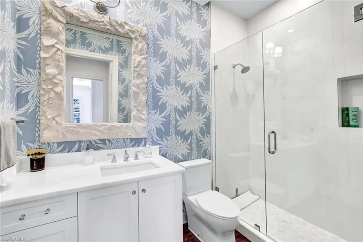 Bathroom with a shower with door, vanity, and toilet