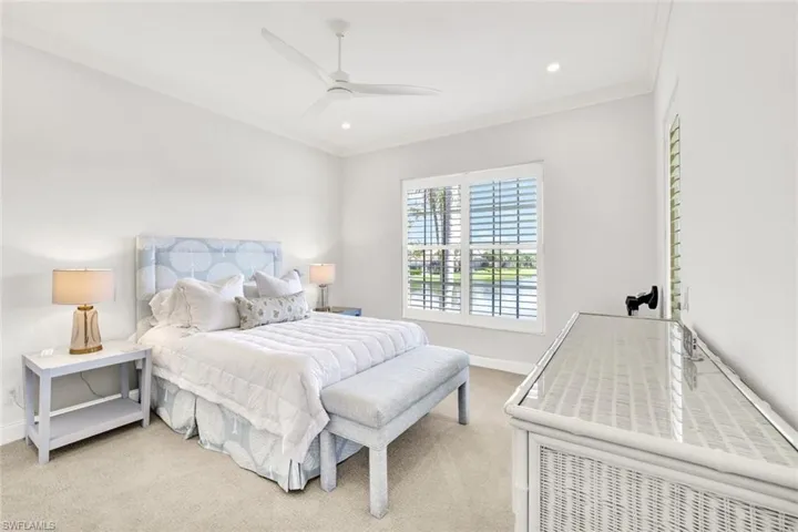 Bedroom with ceiling fan, ornamental molding, and light carpet