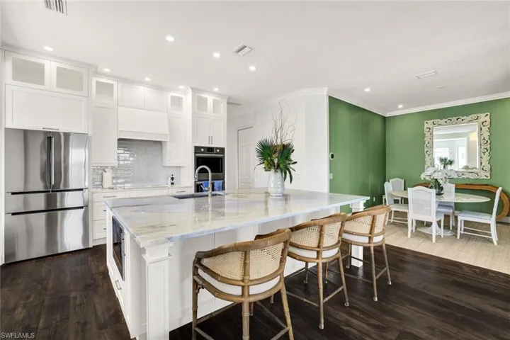 Kitchen with sink, dark wood-type flooring, appliances with stainless steel finishes, white cabinetry, and a spacious island