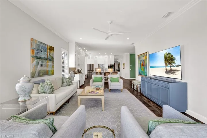 Living room featuring crown molding, dark wood-type flooring, and ceiling fan
