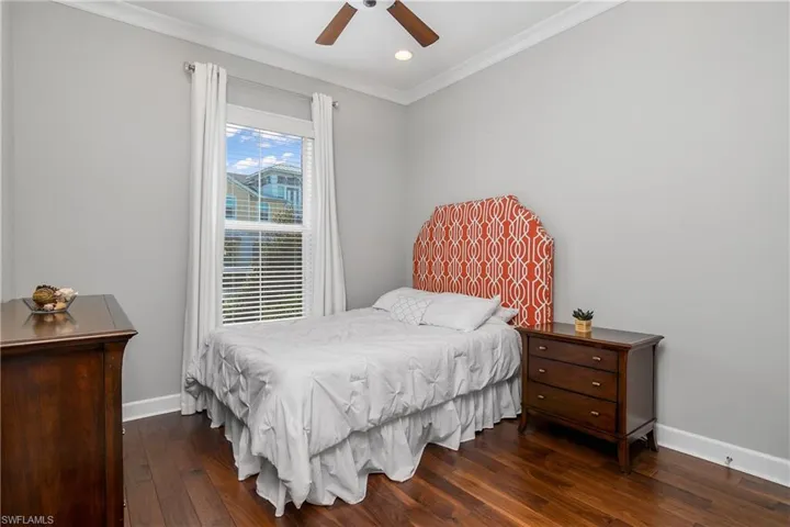 Guest Bedroom featuring ornamental molding, ceiling fan, and hardwood / wood-style flooring.