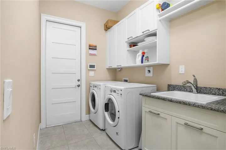 Huge Laundry room, featuring separate washer and dryer, sink, light tile patterned floors, and cabinets. 8 foot Shaker Style Doors throughout. Laundry Sink. Lots of Storage.