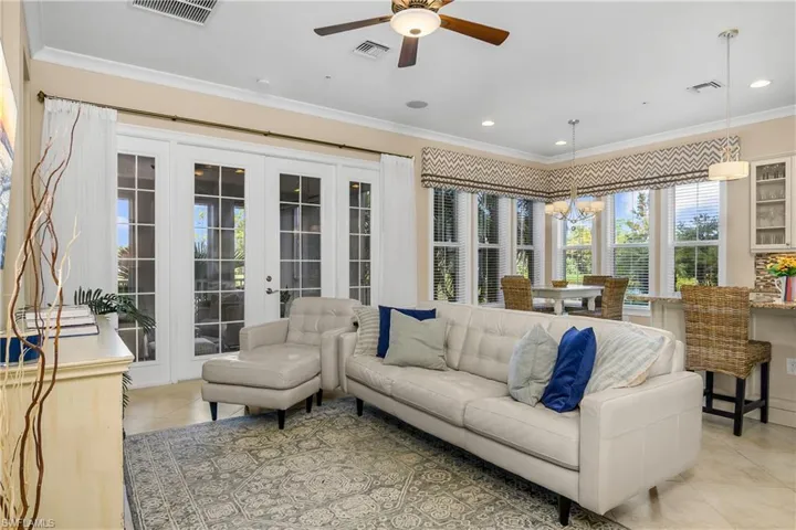 Another angle of the Living room featuring french doors, light tile patterned flooring, ceiling fan, and ornamental molding.