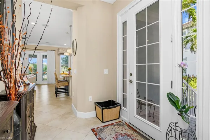 Tiled entrance foyer with french doors with side light windows, and crown molding. A Very welcoming entry!