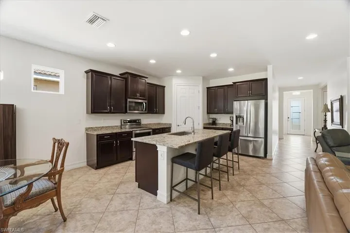 Kitchen featuring healthy amount of natural light, dark brown cabinetry, stainless steel appliances, and recessed lighting