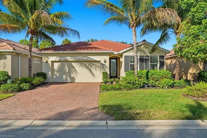 View of front of home with stucco siding, an attached garage, decorative driveway, a tiled roof, and a front lawn