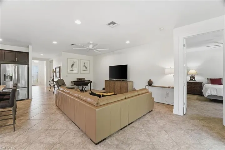 Living room with a ceiling fan, recessed lighting, and light tile patterned floors