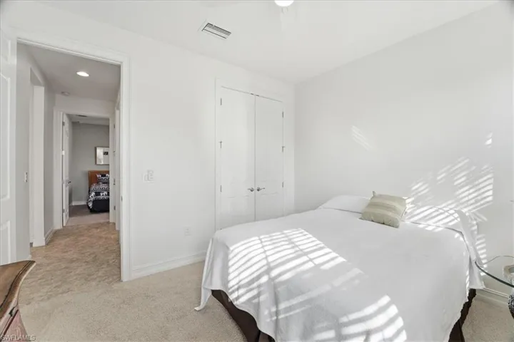 Bedroom with light colored carpet, a closet, and a ceiling fan