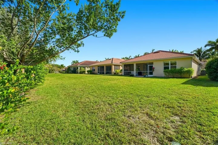 Rear view of property with a sunroom, a lawn, stucco siding, and a tile roof