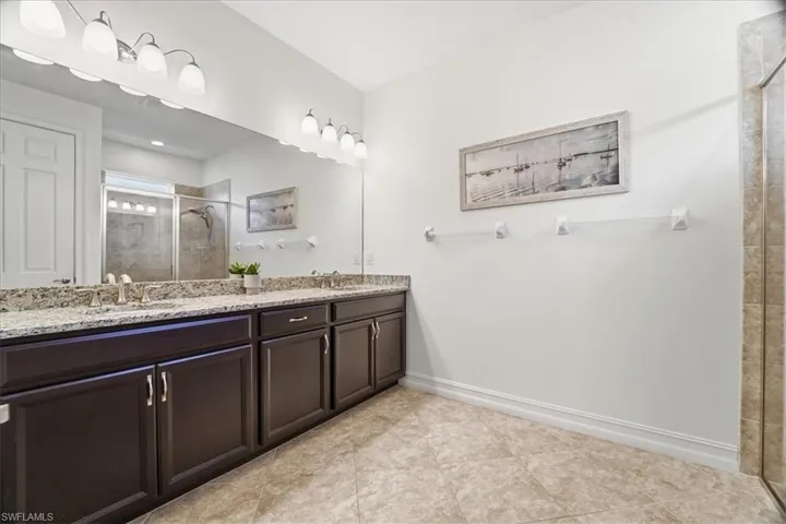 Bathroom featuring a shower stall, double vanity, and light tile patterned floors