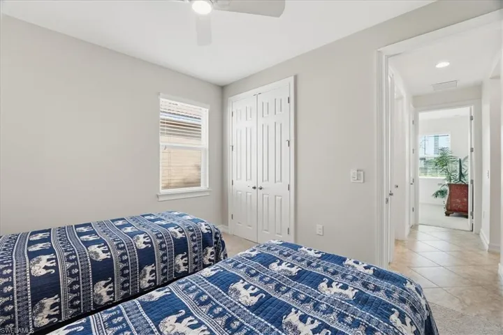 Tiled bedroom with a closet, ceiling fan, and carpet