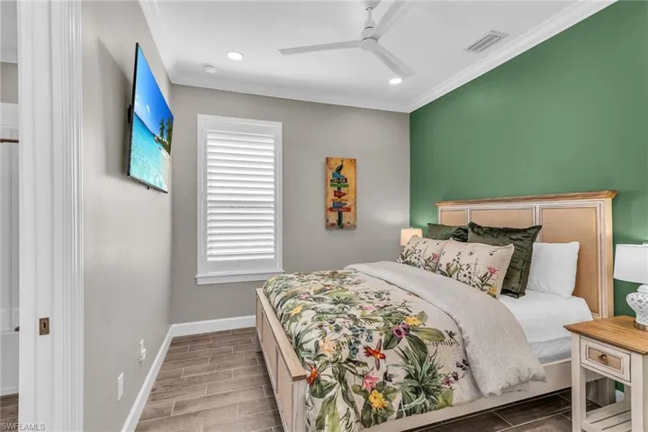 Bedroom featuring wood tiled floor, crown molding, visible vents, and baseboards