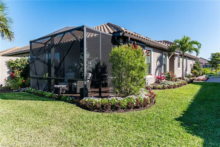 Back of property featuring a tiled roof, a yard, a lanai, and stucco siding
