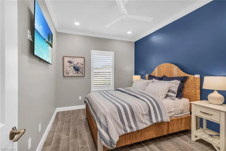 Bedroom with wood tiled floor, multiple windows, baseboards, and ornamental molding