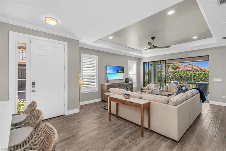 Living area featuring baseboards, a tray ceiling, crown molding, and wood tiled floor