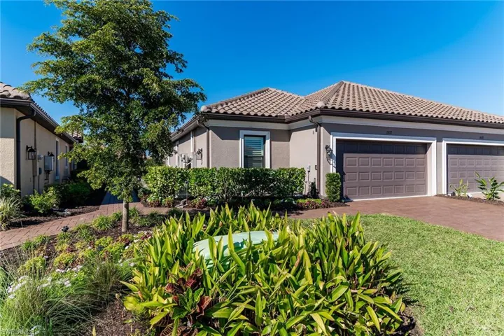 Mediterranean / spanish-style house featuring a garage, driveway, a tile roof, and stucco siding