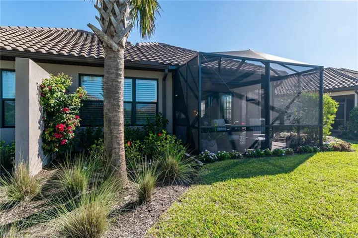 Rear view of property featuring a yard, a tile roof, a lanai, and stucco siding