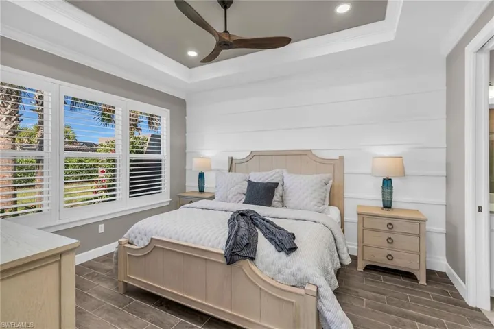 Bedroom with ornamental molding, a tray ceiling, wood finish floors, and baseboards