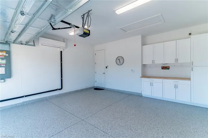 Garage featuring a garage door opener, a wall unit AC, and baseboards
