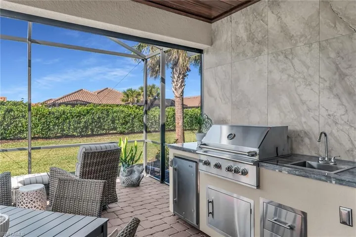 View of patio with a sink, exterior kitchen, a lanai, and a grill