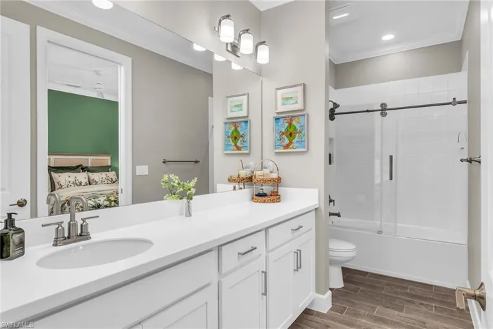 Bathroom featuring wood finish floors, toilet, ornamental molding, vanity, and ensuite bath