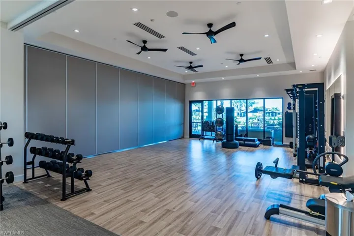 Gym featuring light wood finished floors, a raised ceiling, and visible vents