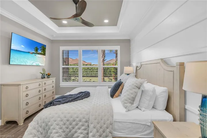 Bedroom with ceiling fan, wood finished floors, a tray ceiling, crown molding, and recessed lighting