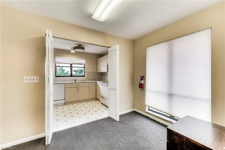 Kitchen with light countertops, light colored carpet, white appliances, and cream cabinets