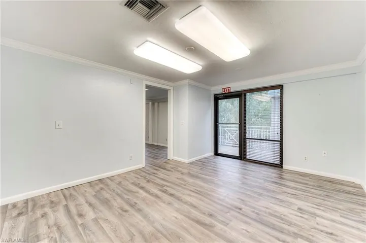 Empty room with ornamental molding and light wood-style flooring