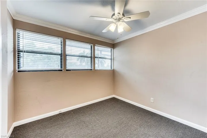 Spare room featuring ornamental molding, carpet flooring, and a ceiling fan