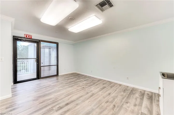 Empty room with ornamental molding and light wood-style flooring