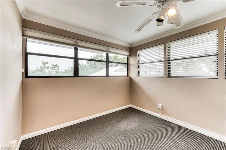 Empty room with carpet flooring, ornamental molding, a ceiling fan, and a textured wall