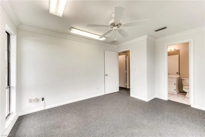Unfurnished bedroom with ornamental molding, carpet, ceiling fan, and ensuite bathroom