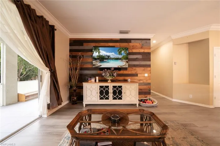 Detailed view of crown molding, wood finished floors, baseboards, wooden walls, and recessed lighting