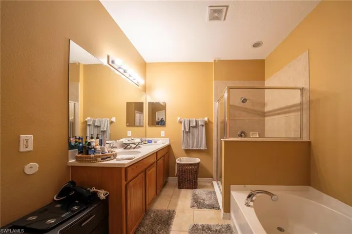 Full bath featuring a shower stall, a bath, tile patterned flooring, and double vanity