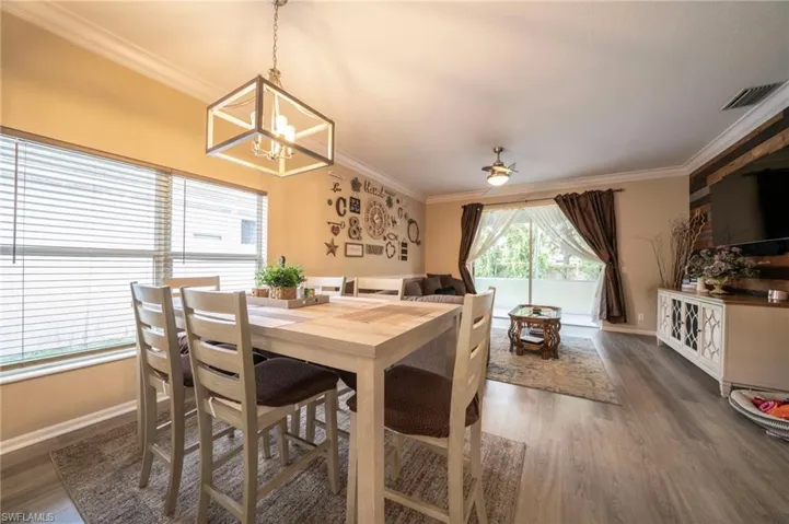 Dining room with a chandelier, ornamental molding, wood finished floors, baseboards, and a ceiling fan
