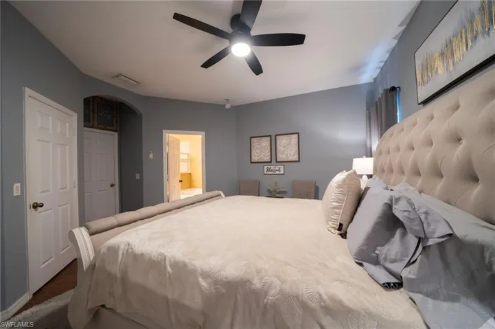 Bedroom with arched walkways, ceiling fan, and ensuite bathroom