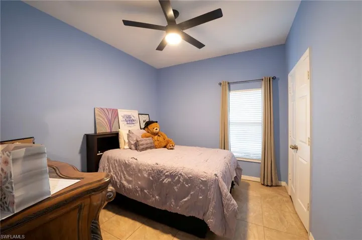 Bedroom featuring light tile patterned flooring, baseboards, and a ceiling fan