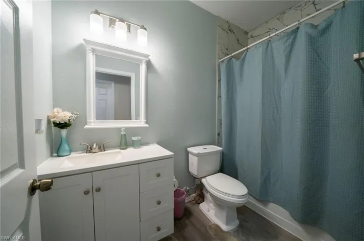 Full bathroom with wood finished floors, vanity, and toilet
