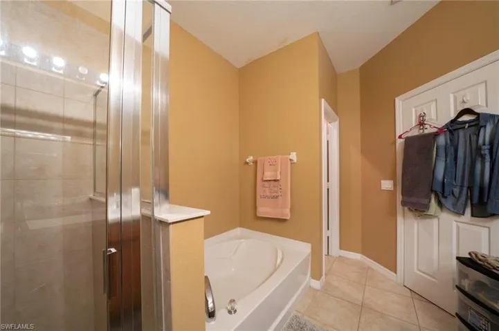 Bathroom with a stall shower, a bath, tile patterned flooring, and baseboards