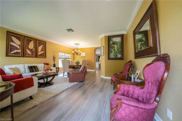 Living area featuring a chandelier, wood finished floors, crown molding, and baseboards