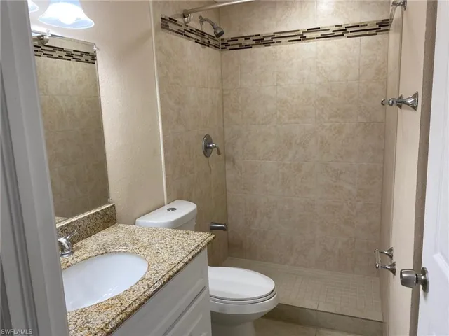 Bathroom with a textured wall, vanity, and a shower stall