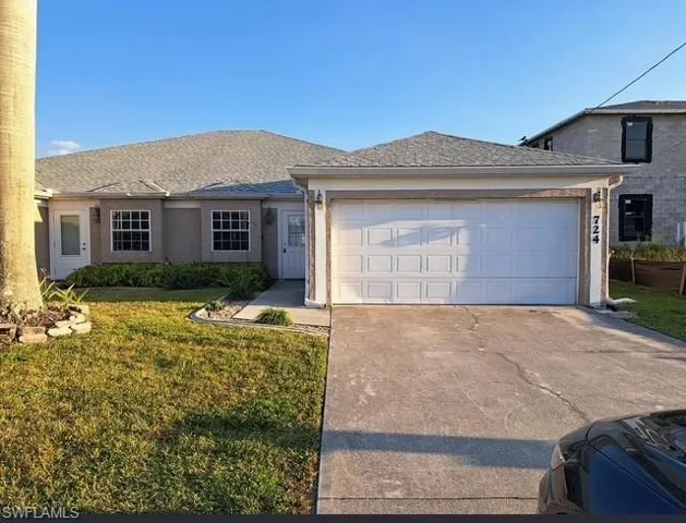 View of front of house featuring driveway, a front yard, a garage, and a shingled roof