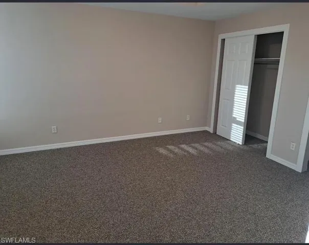 Unfurnished bedroom featuring dark colored carpet and a closet