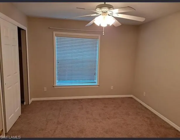 Unfurnished room with ceiling fan and light colored carpet