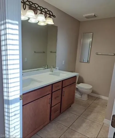 Bathroom with double vanity and light tile patterned floors