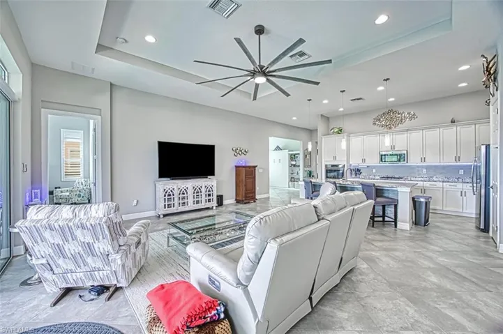 Tiled living room featuring ceiling fan and a raised ceiling