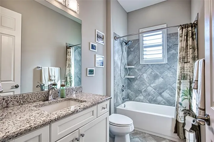 Full bathroom with tile patterned flooring, toilet, vanity, and shower / tub combo